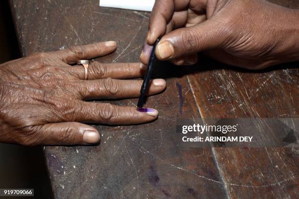 An Indian polling official marks indelible ink on a woman's finger after casting her vote at a polling station during Tripura legislative assembly...