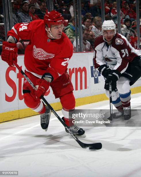 Brad May of the Detroit Red Wings tries to control the puck behind the net against TJ Galiardi of the Colorado Avalanche during a NHL game at Joe...