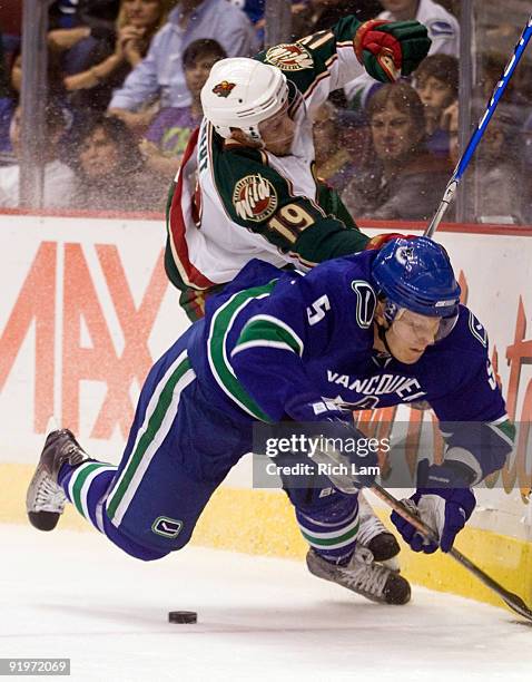 Christian Ehrhoff of the Vancouver Canucks crashes to the ice after colliding with Andy Hilbert of the Minnesota Wild during the first period of NHL...