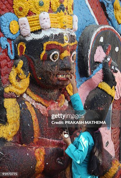 Nepalese Hindu woman offers prayers in front of a statue of Hindu God of Destruction Kaal Bhairab at Durbar Square in Kathmandu on October 18, 2009....