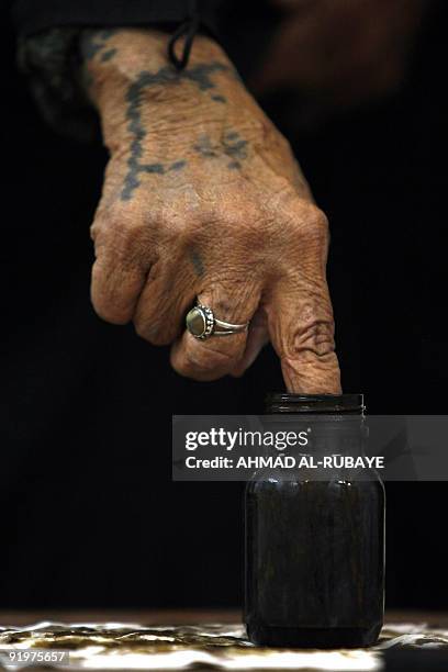 An Iraqi woman with traditional tatooes on her hand dips her finger in indelible ink as she casts her ballot in a primary for supporters of radical...