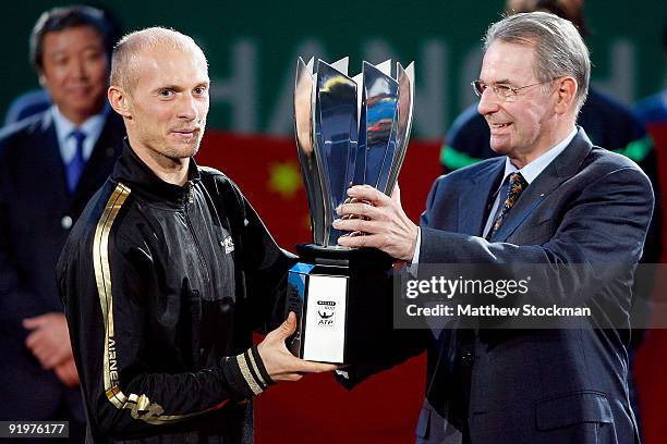 Nikolay Davydenko of Russia is presented with the champions trophy by IOC President Jacques Rooge after defeating Rafael Nadal of Spain during the...