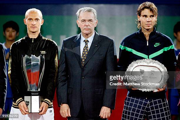 Nikolay Davydenko of Russia and Rafael Dadal of Spain pose for photographers with IOC President Jacques Rogge during the final on day eight of the...