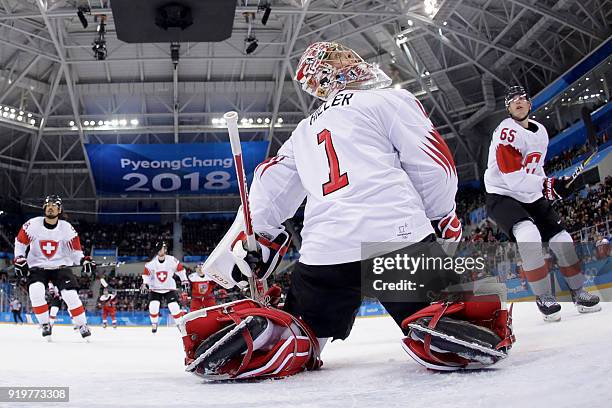 Switzerland's Jonas Hiller and teammate Ramon Untersander look for the puck in the air in the men's preliminary round ice hockey match between the...