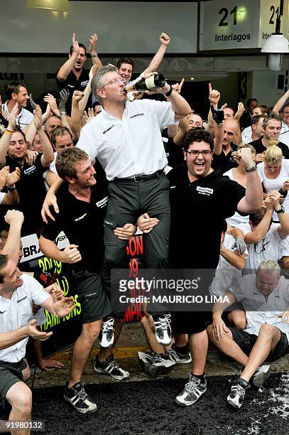 Ross Brawn , owner of Brawn GP team drinks champagne as team members raise him celebrating Jensen Button's World Championship at the end of Brazil's...