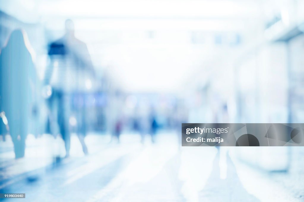 Abstract background of empty space with silhouettes of people passing by