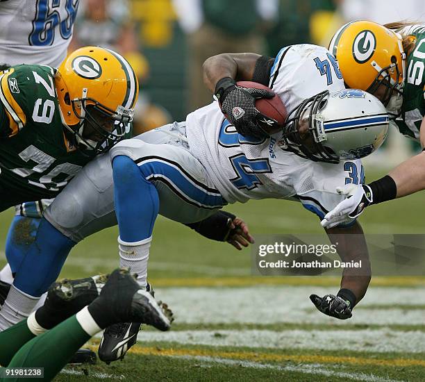 Kevin Smith of the Detroit Lions is tackled by Ryan Pickett and A.J. Hawk of the Green Bay Packers at Lambeau Field on October 18, 2009 in Green Bay,...