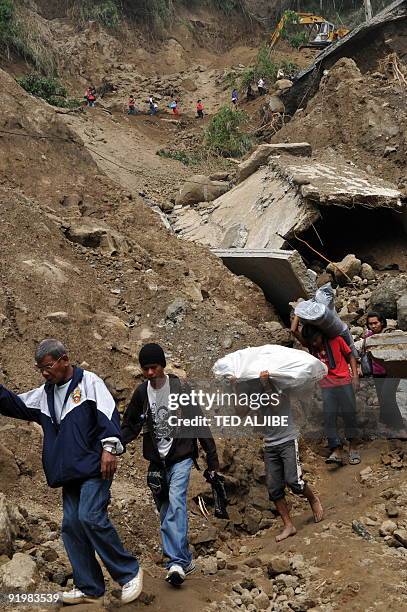 Photo taken on October 12, 2009 shows stranded commuters walking a footpath below a collapsed highway in the town of Tuba, Benguet province near...