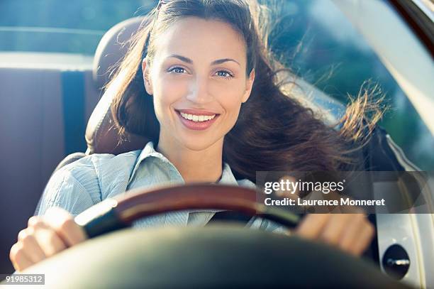 smiling dark-haired woman driving a convertible - sitting on top of car stock pictures, royalty-free photos & images