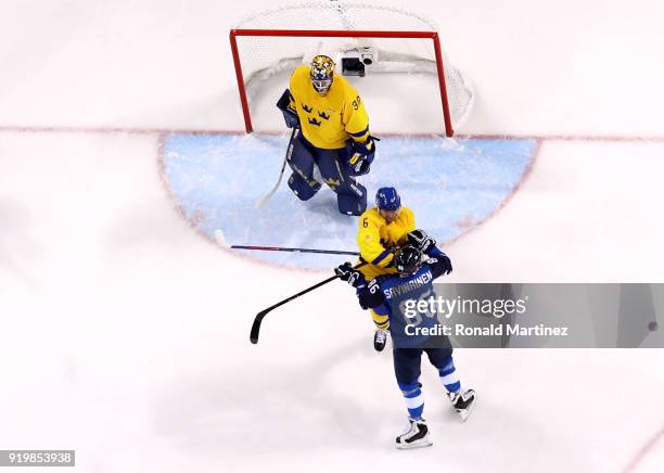 Patrik Hersley of Sweden throws a punch against Veli-Matti Savinainen of Finland in the first period during the Men's Ice Hockey Preliminary Round...