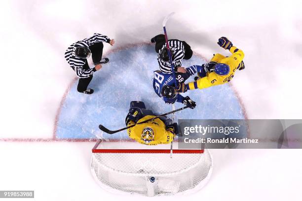 Referees attempt to separate Patrik Hersley of Sweden and Veli-Matti Savinainen of Finland in the first period during the Men's Ice Hockey...