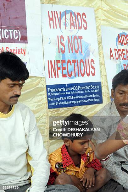 An Indian woman places 'tilak', a religious holy mark of sandalwood paste, on the forehead of an HIV-positive child in observance of 'Bhai Phota'...