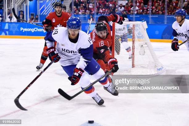 South Korea's Kim Sangwook fights for the puck with Canada's Marc-Andre Gragnani in the men's preliminary round ice hockey match between Canada and...