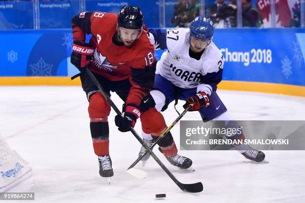 Canada's Marc-Andre Gragnani and South Korea's Ahn Jin Hui fight for the puck in the men's preliminary round ice hockey match between Canada and...