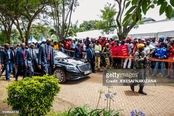 The official limousine of Zimbabwe's president is escorted by close security as mourners including family and opposition party supporters look on...