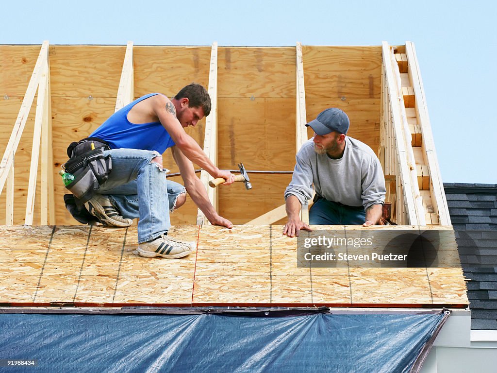 Construction workers on a roof of home