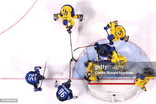Veli-Matti Savinainen of Finland attempts a shot against Oscar Moller and goalie Viktor Fasth of Sweden in the third period during the Men's Ice...