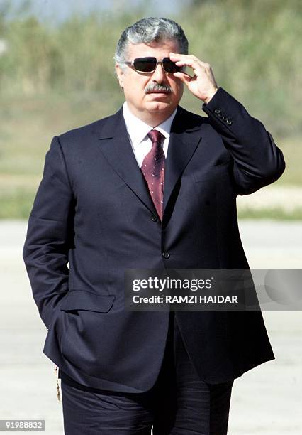 Lebanese Prime Minister Rafiq Hariri adjusts his sunglasses as he awaits the arrival of Syrian President Bashar al-Assad at Beirut airport 03 March...