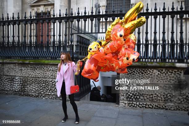 Woman holding balloons waits before taking part a parade to celebrate the Chinese Lunar New Year in central London on February 18, 2018. - The...