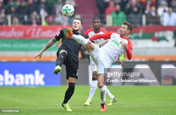 Daniel Ginczek of Stuttgart and Daniel Baier of Augsburg compete for the ball during the Bundesliga match between FC Augsburg and VfB Stuttgart at...