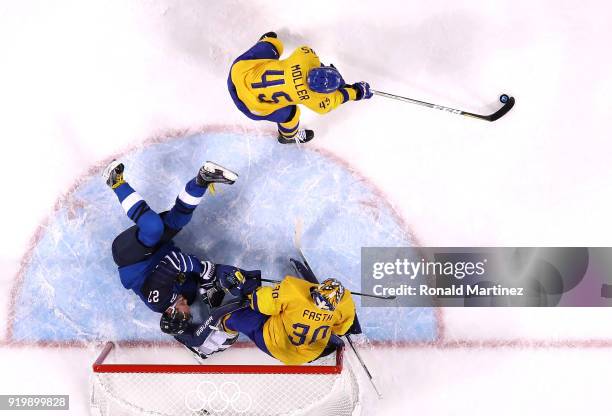 Petri Kontiola of Finland falls in front of goalie Viktor Fasth of Sweden as Oscar Moller attempts to clear the puck in the third period during the...