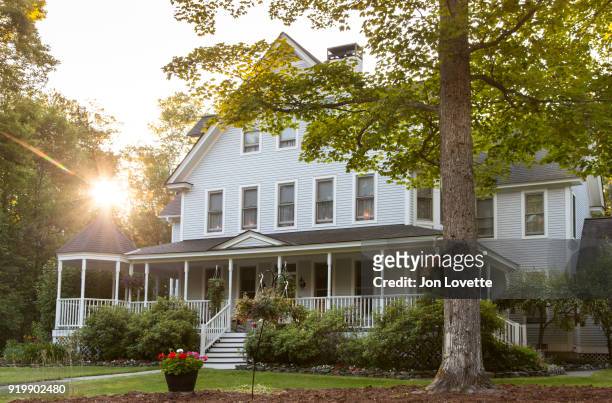 victorian home with lawn and large front porch in summer at sunset - portico sopraelevato foto e immagini stock