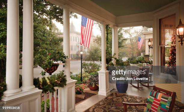 front porch and gardens with american flag - porch stock-fotos und bilder