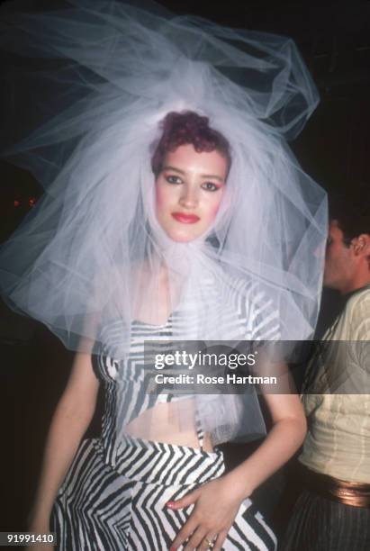 Portrait of an unidentified party-goer at the nightclub Studio 54, New York, New York, late 1970s or early 1980s. She wears a large taffeta headpiece...