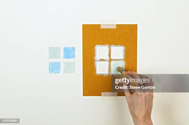 man using stencil and paintbrush to create pattern on wall - schablone stock-fotos und bilder