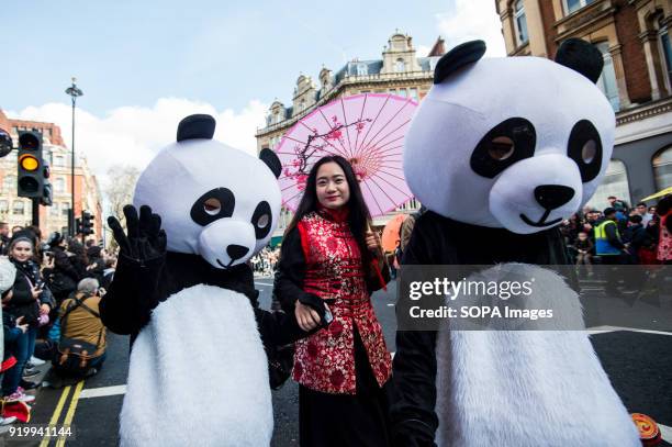 Woman dressed with traditional clothes seen posing for a picture near a panda character on the Chinatown streets during the Chinese New Year...