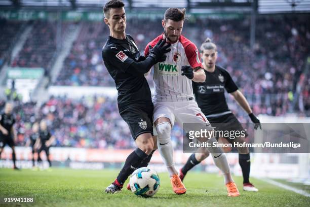Marcel Heller of Augsburg is tackled by Erik Thommy of Stuttgart during the Bundesliga match between FC Augsburg and VfB Stuttgart at WWK-Arena on...