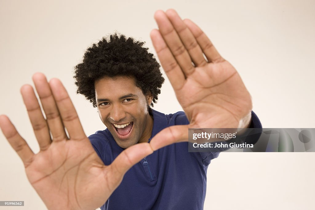 Man framing camera with his hands, smiling.