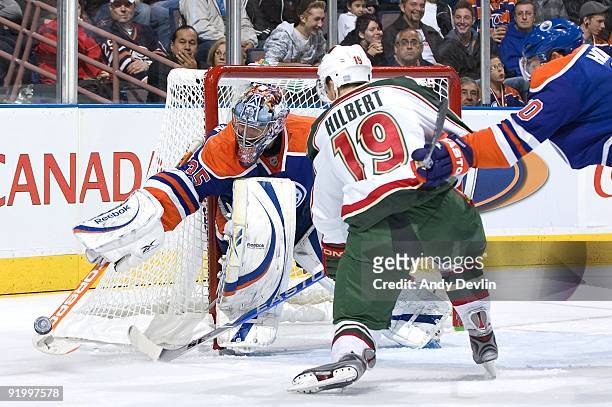 Nikolai Khabibulin of the Edmonton Oilers makes a save under pressure from Andy Hilbert of the Minnesota Wild at Rexall Place on October 16, 2009 in...