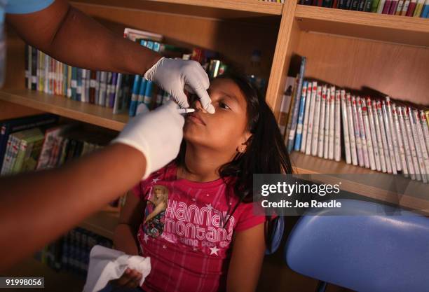 Johana Villafuerte receives a H1N1 nasal flu spray vaccine from nurse Shajaira Powell-Bailey at the Broadmoor Elementary school October 19, 2009 in...