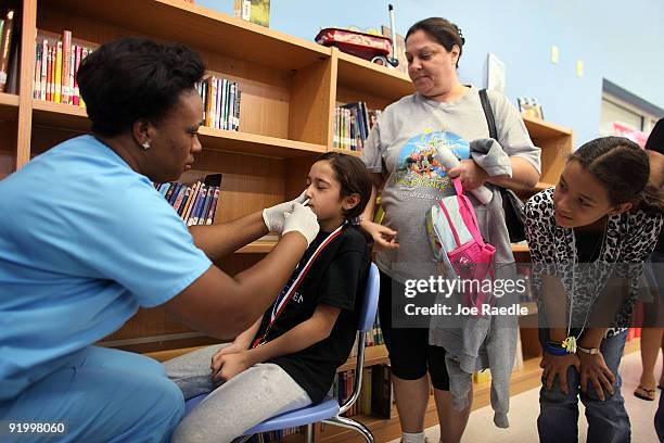 Stephanie Rojas receives an H1N1 nasal flu spray vaccine from nurse Shajaira Powell-Bailey at the Broadmoor Elementary school October 19, 2009 in...
