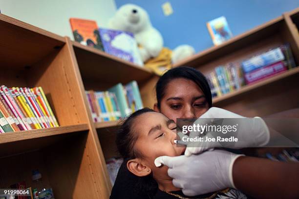 Iris Luna holds Ashley Luna as she receives a H1N1 vaccination from nurse Shajaira Powell-Bailey at the Broadmoor Elementary school October 19, 2009...