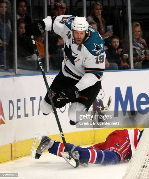 Joe Thornton of the San Jose Sharks jumps over Dan Girardi of the New York Rangers at Madison Square Garden on October 19, 2009 in New York City.