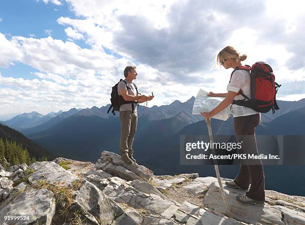 couple look at map and compass, on mtn ridge - bergsteiger mit karte und rucksack stock-fotos und bilder