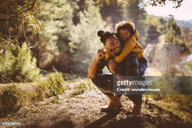 padre e hijo divertirse con piggyback ride en bosque - kids fitness fotografías e imágenes de stock