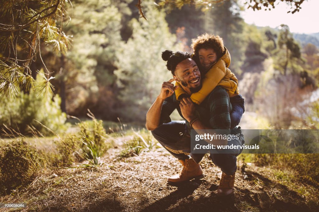Father and son having fun with piggyback ride in forest