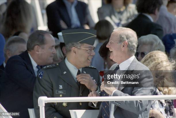 Secretary of State James Baker and General Colin Powell, chairman of the Joint Chiefs of Staff, share a laugh on the reviewing stand before the start...