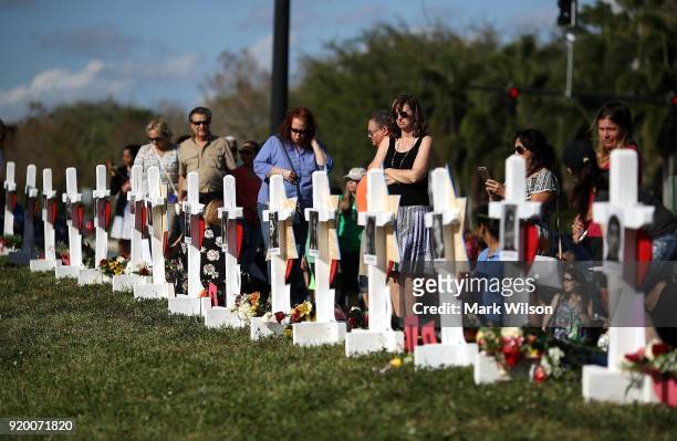 People visit a makeshift memorial in front of the Marjory Stoneman Douglas High School where 17 people were killed on February 14, on February 18,...