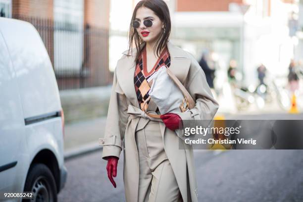 Doina Ciobanu wearing red leather gloves, grey pants, grey trench, v neck sweater seen outside Temperley London during London Fashion Week February...