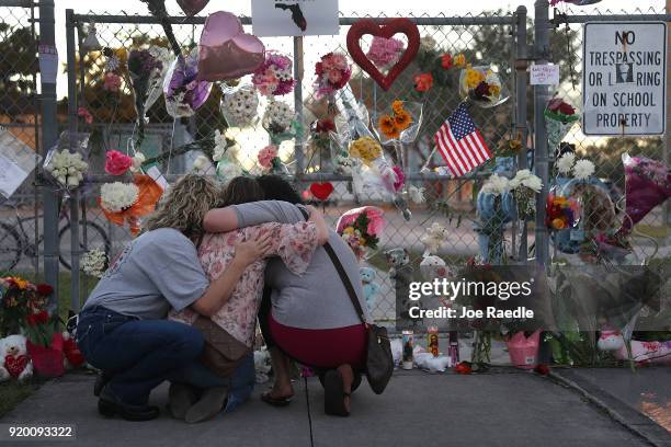 Shari Unger, Melissa Goldsmith and Giulianna Cerbono hug each other as they visit a makeshift memorial setup in front of Marjory Stoneman Douglas...