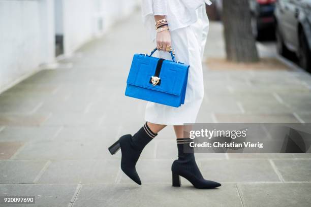 Nina Suess wearing total look Marc Cain including white off shoulder blouse, white cropped wide leg pants, blue bag, sock boots seen during London...