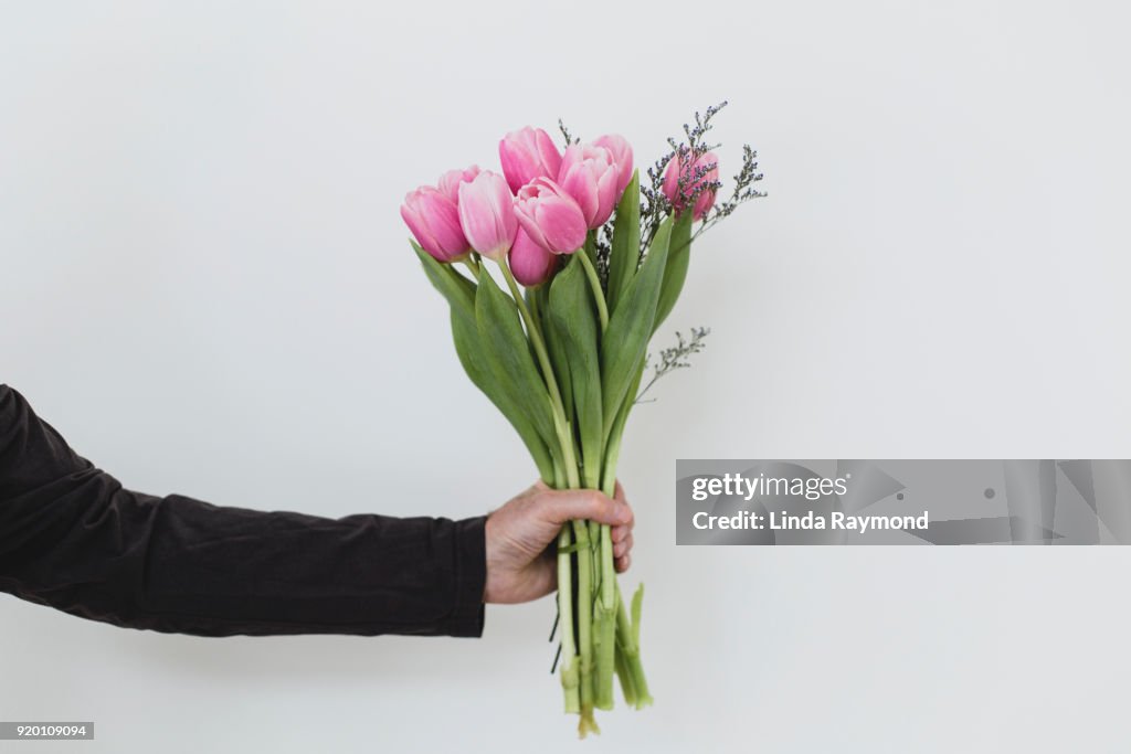 Bouquet of tulips in a hand against a light blue background