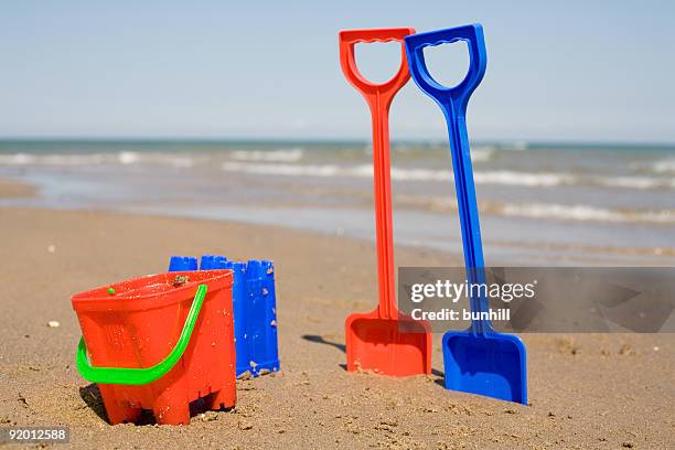 buckets and spades in the sand at beach - sand pail and shovel stock pictures, royalty-free photos & images