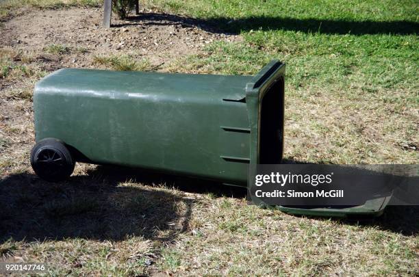 overturned plastic wheeled garbage bin on a grass verge - wheeled garbage can stock pictures, royalty-free photos & images