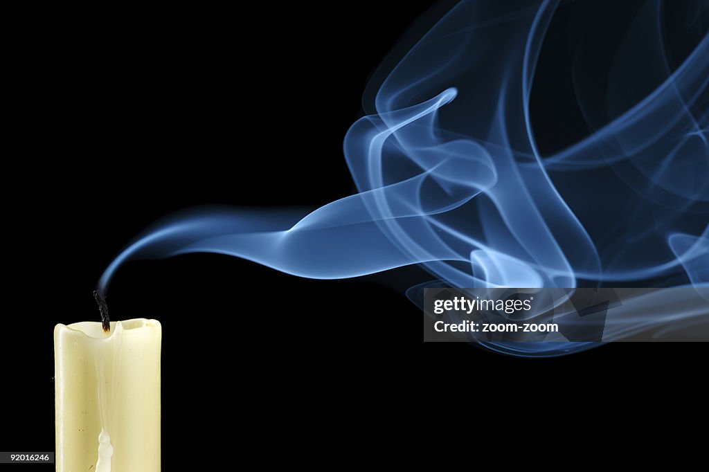 Close-up of white extinguished candle with curling up smoke