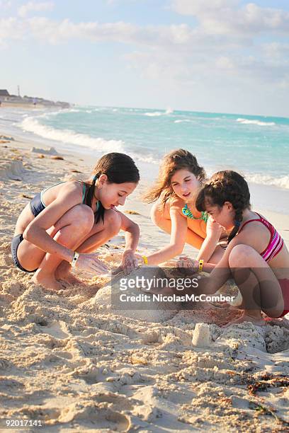 girls building sand castle - beige boot stockfoto's en -beelden